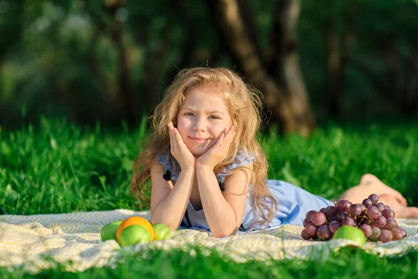 Szczęśliwa dziewczynka bawiąca się w parku. Cute dziecko siedzi na trawie w słoneczny letni dzień. — Zdjęcie stockowe