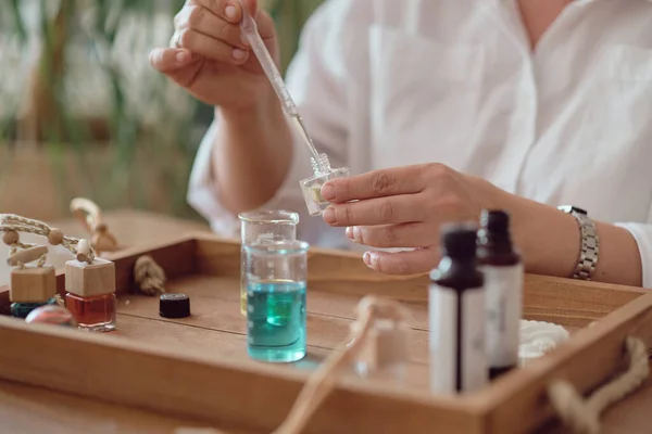 用油和玻璃瓶做特写的特写女人在瓶子里倒香水。香水创作工作坊 — 图库照片