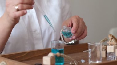 Yağlı ve cam şişeli bir pipetin yakın çekimi. Kadın şişeye parfüm döküyor. Parfüm atölyesi oluşturma