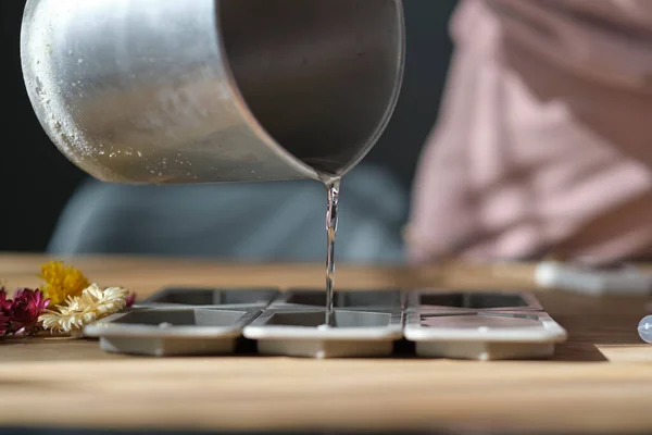 Femme verse de la cire d'abeille dans un moule en silicone pour faire des bougies — Photo