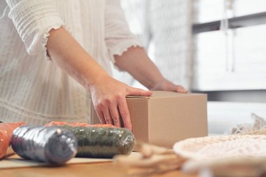 Kadın girişimci, karton bir kutuya el yapımı bir ürün koyar. Küçük bir iş için mal teslimatı. Yaşlı bir kadın hobisini evde kazanır..