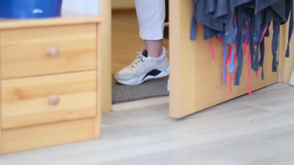 Onherkenbare vrouw in witte sneakers die naar binnen gaat. de hond volgt de eigenaar. Slow Motion Schot — Stockvideo