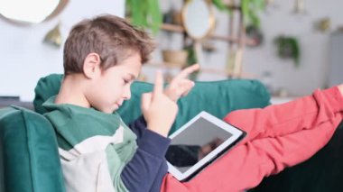 Küçük çocuk evde dijital tabletle oynarken gülümsüyor. Modern çocuk ve eğitim teknolojisi. Küçük çocuk evdeki dokunmatik yere bakıyor..