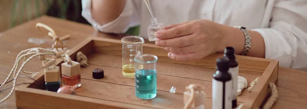 Gros plan d'une pipette avec de l'huile et une bouteille en verre. femme versant du parfum en bouteille. Atelier de création de parfum — Photo