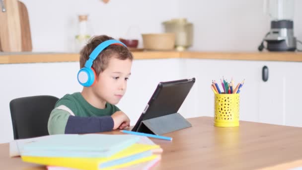 Estudiante inteligente escuchar lecciones en línea sobre la tableta usar auriculares Spbas. Homeschooled niño reloj. — Vídeos de Stock