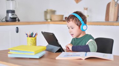 Akıllı çocuk tablet hakkında online ders dinliyor kulaklık takıyor Spbas. Evde eğitim görmüş çocuk gözetimi.