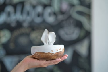 Tanımlanamayan kadın seramikçi elinde bitmiş bir ürün tutuyor. Tavşan kulaklı bir kase. Yaratıcılık kavramı, seramik alanında usta bir sınıfın reklamı..