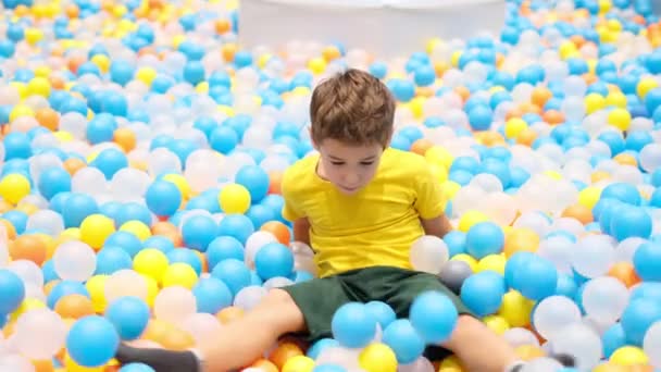 Niño jugando en el parque infantil piscina de bolas de colores. Felicidad en colores brillantes. — Vídeos de Stock