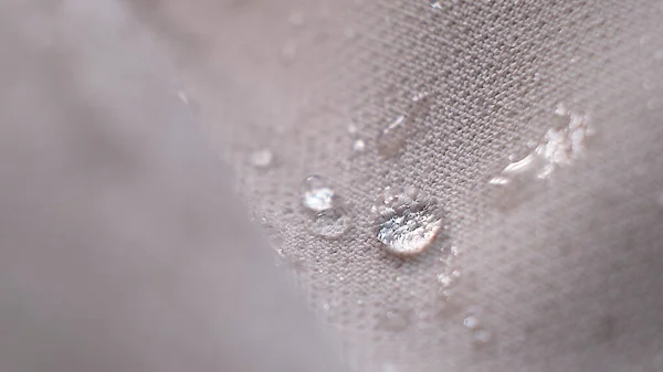 Abalorios de agua en la tela. Fondo de revestimiento impermeable con gotas de agua. enfoque suave, desenfoque —  Fotos de Stock