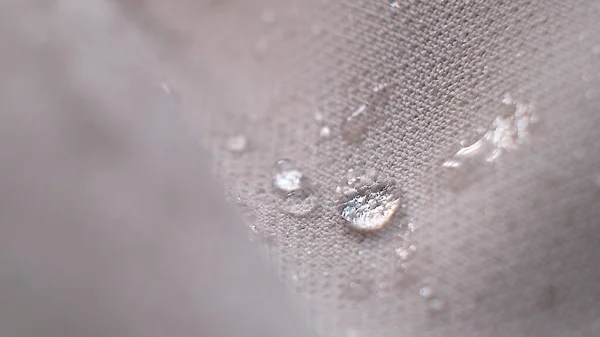 Abalorios de agua en la tela. Fondo de revestimiento impermeable con gotas de agua. enfoque suave, desenfoque — Foto de Stock