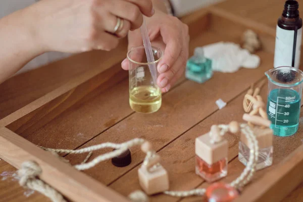 用油和玻璃瓶做特写的特写女人在瓶子里倒香水。香水创作工作坊 — 图库照片