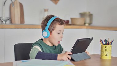 Akıllı çocuk tablet hakkında online ders dinliyor kulaklık takıyor Spbas. Evde eğitim görmüş çocuk gözetimi.