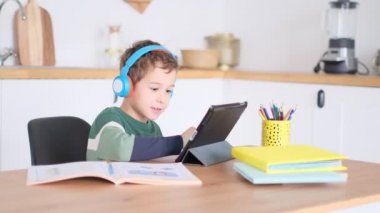 Akıllı çocuk tablet hakkında online ders dinliyor kulaklık takıyor Spbas. Evde eğitim görmüş çocuk gözetimi.