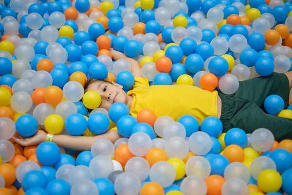 Çocuk oyun parkında renkli top havuzunda oynuyor. Parlak renklerde mutluluk.