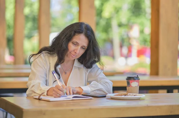 Mulher idosa elegante alegre sorrindo. Tiro na cabeça de perto retrato feliz mulher de meia-idade saudável sentado em um café, escreve seus pensamentos em um diário — Fotografia de Stock