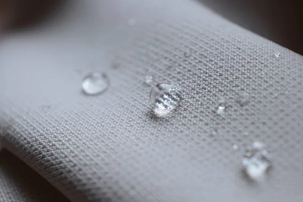 Abalorios de agua en la tela. Fondo de revestimiento impermeable con gotas de agua. enfoque suave, desenfoque —  Fotos de Stock