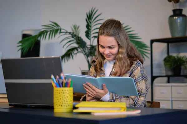 Tinédzser lány házi feladatot csinál egy íróasztalnál a hálószobájában. tini lány iskolás diák írni jegyzetek videó online webinar tanulni laptop. távolság elearning tanfolyam videó konferencia pc hívás. — Stock Fotó