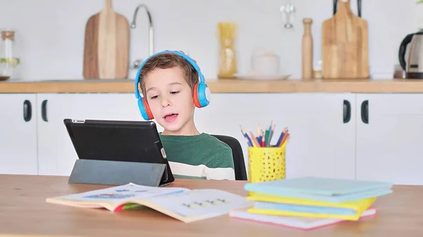 Inteligentny student słuchać lekcji online na tablecie nosić słuchawki Spbas. Zegarek dla dzieci uczących się w domu. — Zdjęcie stockowe