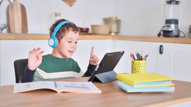 Akıllı çocuk tablet hakkında online ders dinliyor kulaklık takıyor Spbas. Evde eğitim görmüş çocuk gözetimi.