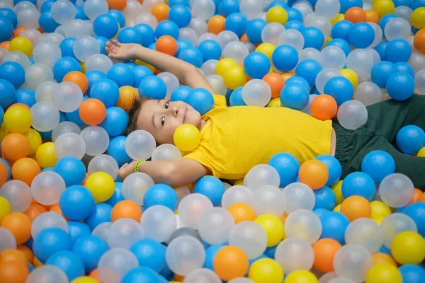 Ragazzo che gioca nel parco giochi colorata piscina palla. Felicità in colori vivaci. — Foto Stock