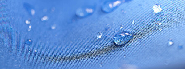 Water drops on the fabric. Rain Water droplets on blue fiber waterproof fabric. Water drops pattern over a waterproof cloth. Blue background.