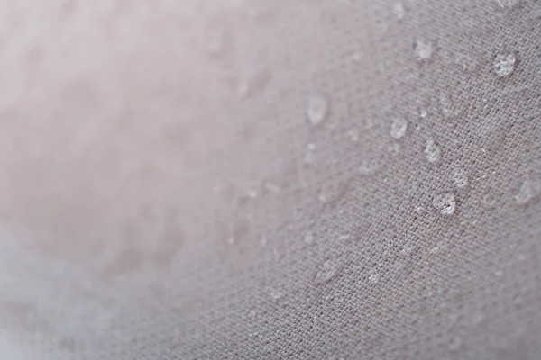 Abalorios de agua en la tela. Fondo de revestimiento impermeable con gotas de agua. enfoque suave, desenfoque — Foto de Stock