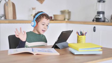 Akıllı çocuk tablet hakkında online ders dinliyor kulaklık takıyor Spbas. Evde eğitim görmüş çocuk gözetimi.
