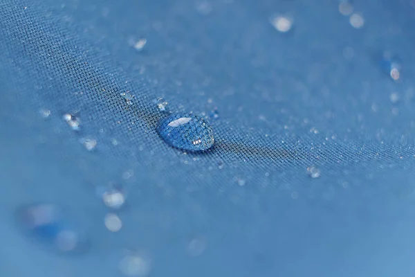 Вода падає на тканину. Вода крапель на синьому волокні водонепроникна тканина. Вода опускає візерунок на водонепроникну тканину. Синій фон . — стокове фото