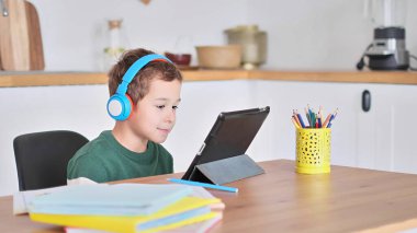 Akıllı çocuk tablet hakkında online ders dinliyor kulaklık takıyor Spbas. Evde eğitim görmüş çocuk gözetimi.