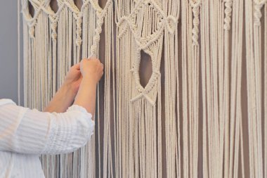 Makrome 'un temel düğümleri, kadın elinin omuz arkasının görüntüsü, düğümleniyor. Çevre dostu modern örgü doğal dekorasyon konsepti.