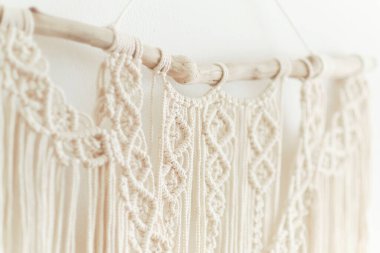 Duvar panelinde güzel bir makrome. Ev dekorasyonu ve düğün dekorasyonu için makrome tekniğini kullanarak doğal renklerde pamuk ipliklerden yapılmış Boho tarzı goblen. açık renkli renkler