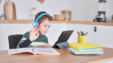Akıllı çocuk tablet hakkında online ders dinliyor kulaklık takıyor Spbas. Evde eğitim görmüş çocuk gözetimi.
