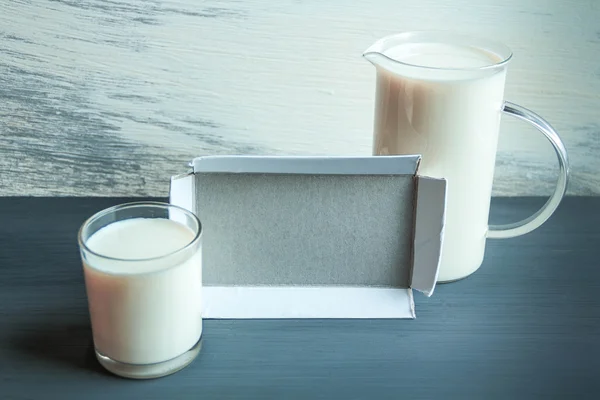 Jarra y taza de vidrio con leche de almendras en la mesa de madera. intolerancia a la lactosa — Foto de Stock