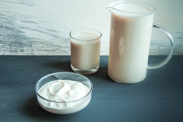 Tazza di brocca e vetro con latte e panna acida sul tavolo di legno. intolleranza senza lattosio — Foto Stock