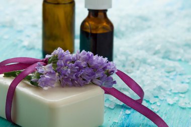 doğal organik sabun şişe esans ve deniz tuzu çiçekli mavi bir ahşap tablo