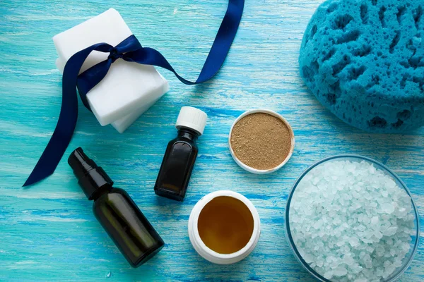 Bottiglie di sapone biologico naturale olio essenziale e sale marino bagno alle erbe su una tavola di legno blu — Foto Stock