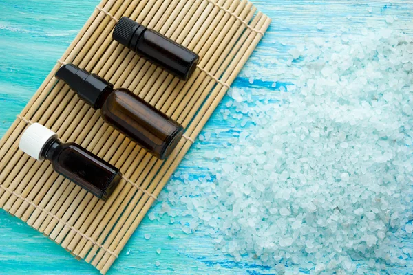 Flessen etherische olie en zeezout op een blauwe houten tafel — Stockfoto