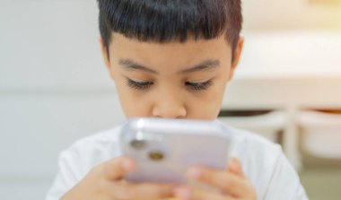 Sevimli küçük çocuğa telefon etmek, ekrana bakmak ya da telefonda çizgi film seyretmek. Cep telefonu dijital aygıtı ve çocuk konsepti.