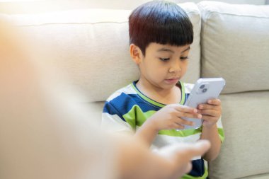 Asyalı anne eli oğlunun oyun bağımlılığını durdurmak için küçük oğlundan cep telefonu istedi. Telefon kavramında ebeveyn kontrolü