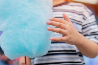 Yaz parkındaki bir çocuğun elinde pamuk şeker. Tatlı yemek ve şeker. Seçici odak, yakın plan.