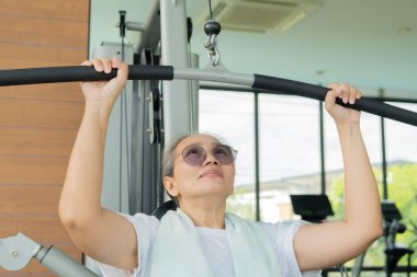 Formda kalmak için spor salonunda egzersiz yapan mutlu Asyalı kadın. Spor salonunda spor yapan olgun bir kadın. Son sınıf spor konsepti.