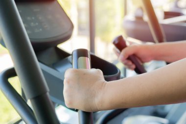 Spor salonunda spor bisikletle antrenman yapmak, bisikletin sapını tutarak olgun bir şekilde yakın çekim yapmak. Spor salonunda kardiyo yapan son sınıf sporcusu. egzersiz konsepti yapıyor.