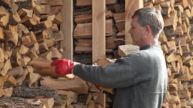 Adam arka bahçesine odun yığarak kışa hazırlanıyor. Bir adam arka bahçesinde düzgünce odun yığıyor ve önümüzdeki soğuk kış aylarına hazırlanıyor.
