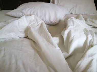 Buruşuk çarşaflı ve yastıklı beyaz yatak rahat bir ortam yaratır. Ev dekorasyonu ve yaşam tarzı içeriği için mükemmel..