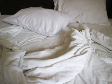 Kırışık beyaz çarşafları ve yastıkları olan dağınık bir yatak rahat, rahat bir atmosfer yaratıyor. Yaşam tarzı ve ev dekorasyonu için mükemmel..