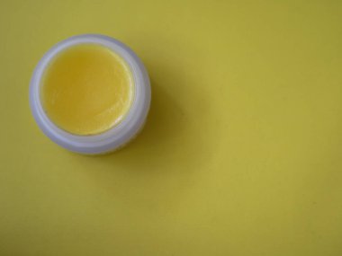 Sarı dudak merhemi kabı parlak sarı yüzeyde hafif ışıklandırma ile güzellik ve cilt pazarlama için ideal yeni ve temiz bir atmosfer yaratıyor..