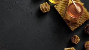 Siyah masadaki bal peteğinin üzerindeki bal kovanı. Yatay kompozisyon 4K UHD video görüntüleri.