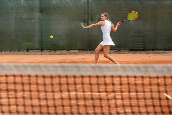 Professional tennis player playing tennis on a clay tennis court on a sunny day