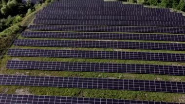 Güneşli bir günde, Yeşil Alan 'daki güneş enerjisi istasyonu. Hava görüntüsü. Güneş Panelleri Güç Üretimi Alanında Bir Satırda Duruyor. İnsansız hava aracı Güneş Çiftliği üzerinde uçuyor. Yenilenebilir yeşil enerji. Alternatif enerji kaynakları