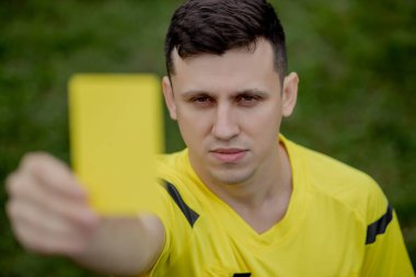 Hakem, hoşnutsuz bir futbol oyuncusu ya da futbolcuya kırmızı kart gösteriyor. Spor anlayışı, kural ihlali, tartışmalı konular, engellerin aşılması